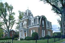 дом из коричневого кирпича с белыми ставнями на окнах и серой крышей